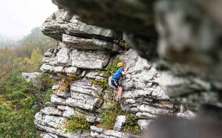 a student scales a rock wall on a rock climbing trip near DC